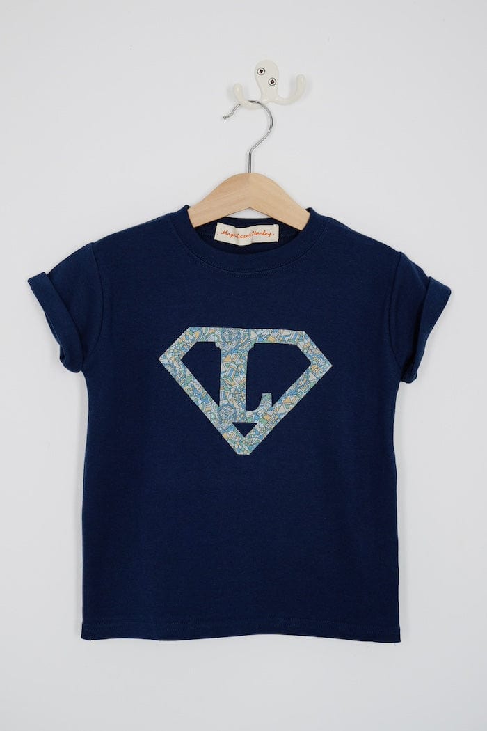 a personalised navy t-shirt with his initial inside a superhero emblem made from Liberty print