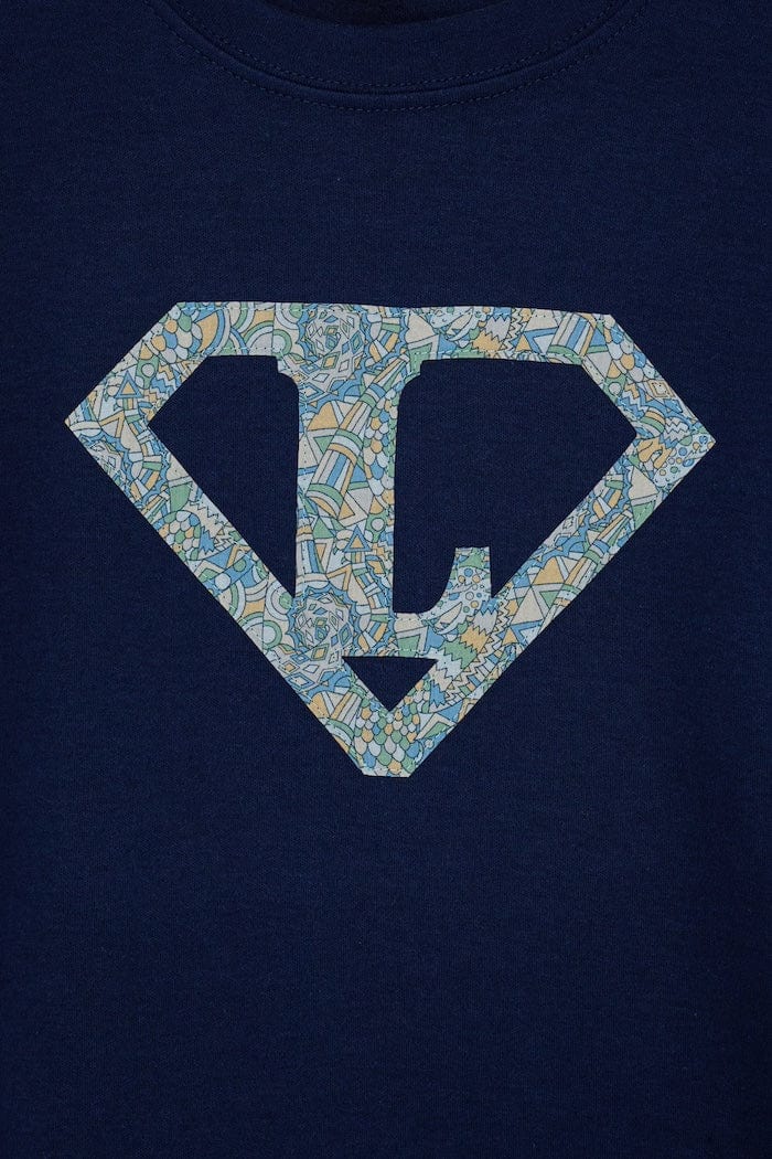 a personalised navy t-shirt with his initial inside a superhero emblem made from Liberty print