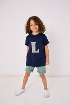 a  3 year old boy wearing a personalised kids navy t-shirt with an initial cut from brave noah dragons print on the front