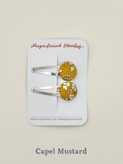 Pair of mustard yellow hair clips with floral  liberty Capel mustard design on a 'Magnificent Stanley' card.