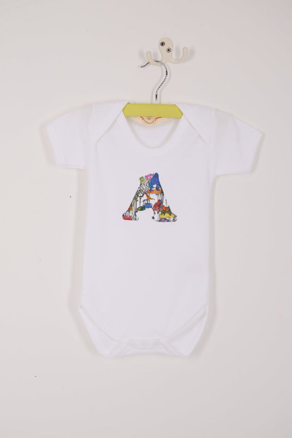 a personalised baby bodysuit with his initial cut from dinosaur liberty print on the front