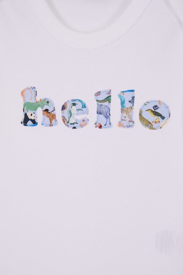 A close up of a white cotton babygrow with the word hello sewn on the front, cut from Quey 2 zoo animal  Liberty print.