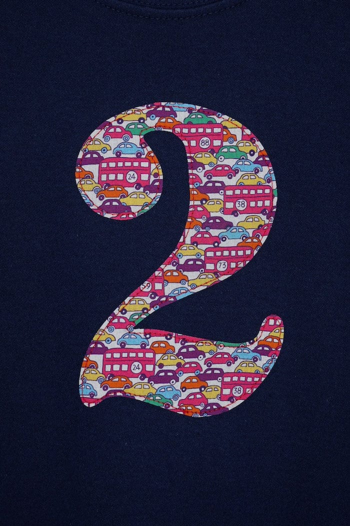 a personalised kids navy t-shirt with an initial cut from hop on hop off liberty print featuring london buses and vintage cars.
