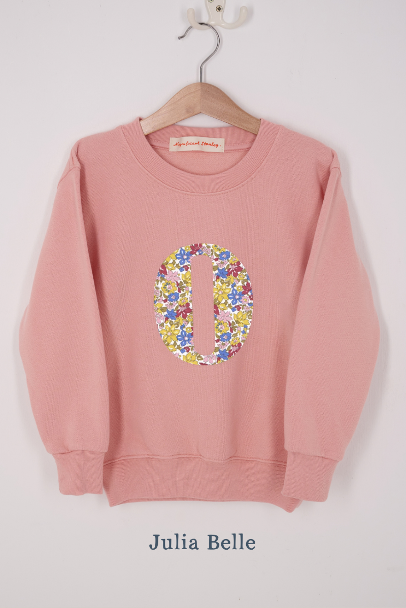 A pink personalised sweatshirt with an initial sewn on to the front. The initial is made from Julia Belle floral liberty print