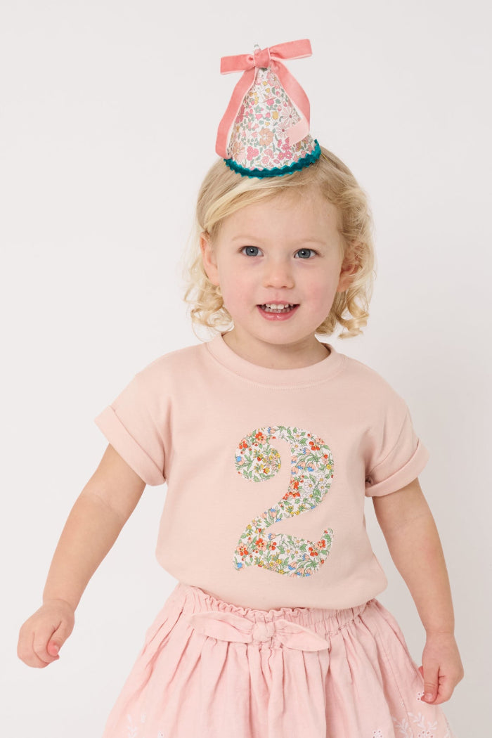 A birthday girl wearing a pale pink t-shirt with a Liberty Nazanin floral number '2' on the front.