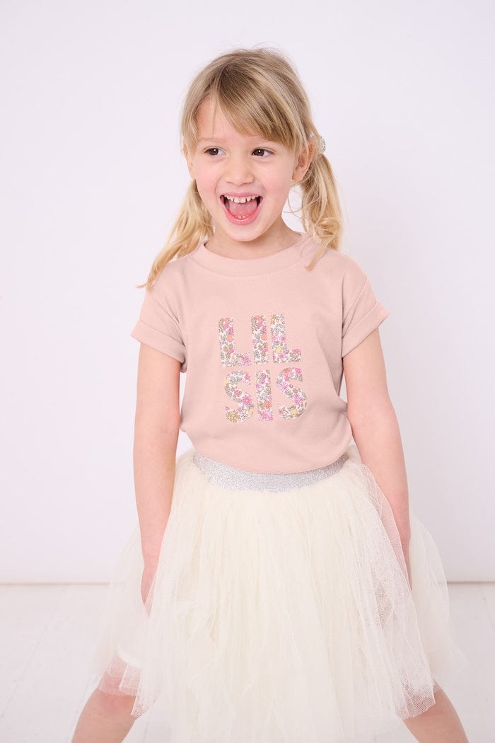 Little sister wearing a pink t-shirt with the words Lil Sis on the front cut from floral Liberty print.