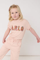 A young girl wearing a pink t-shirt with her name on the front in Liberty Nell Annie May floral print.