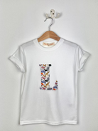 White t-shirt with colorful 'L' design on a hanger against a white background