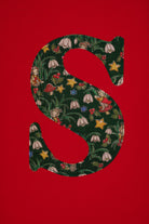 A festive children's outfit set featuring a bright red long-sleeve top with a large green floral monogram letter 'S' on the chest made from Liberty Elves print.