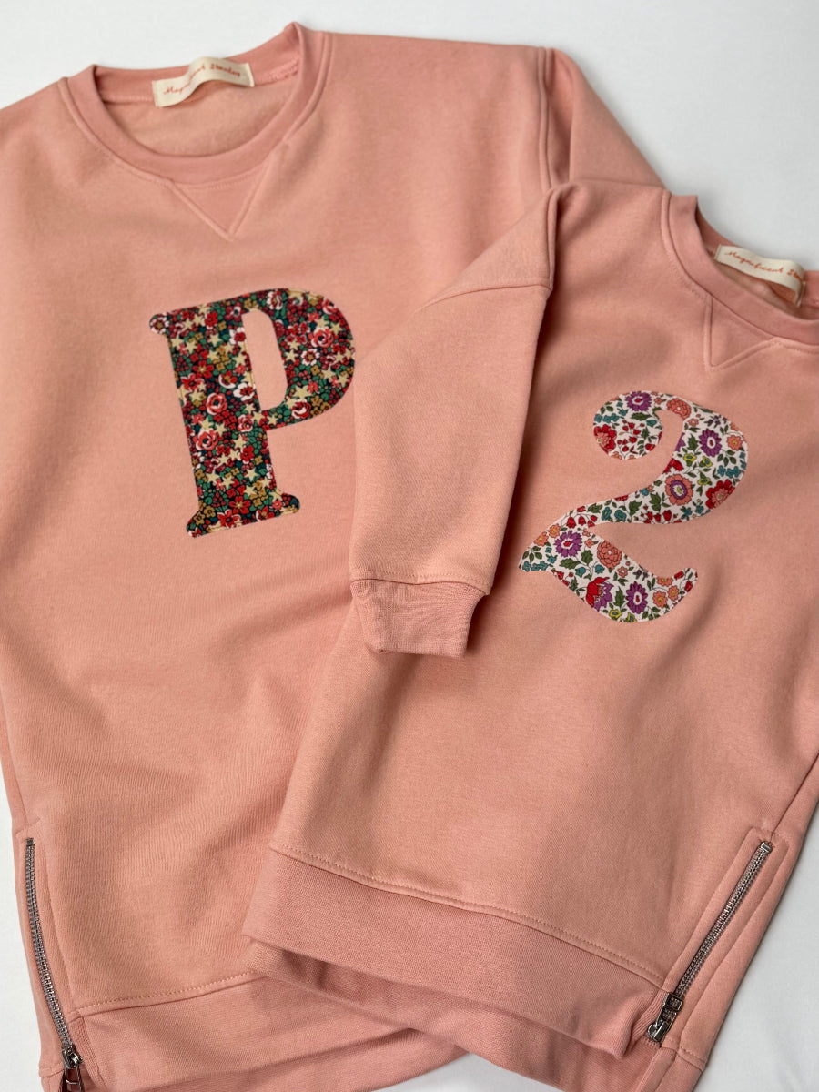 Pink sweatshirt dress with Liberty floral letter 'P' and 'E' on a white background