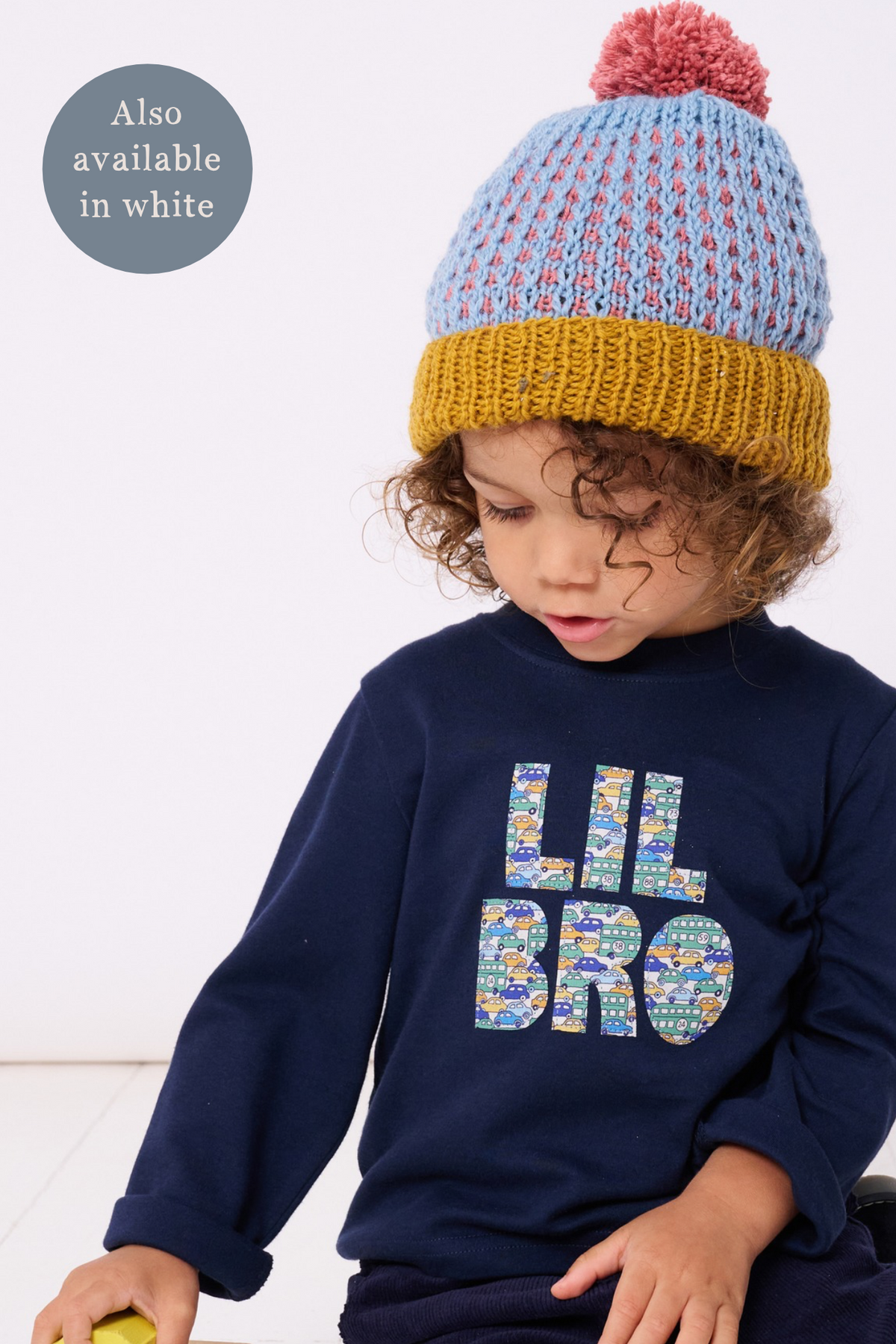 A 3 year old boy little brother wearing a cotton navy t-shirt with the words lil bro on the front cut from Liberty cars and buses print.