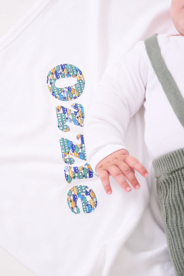 A new baby boy laying on a cotton baby Blanket personalised with his name in Liberty print
