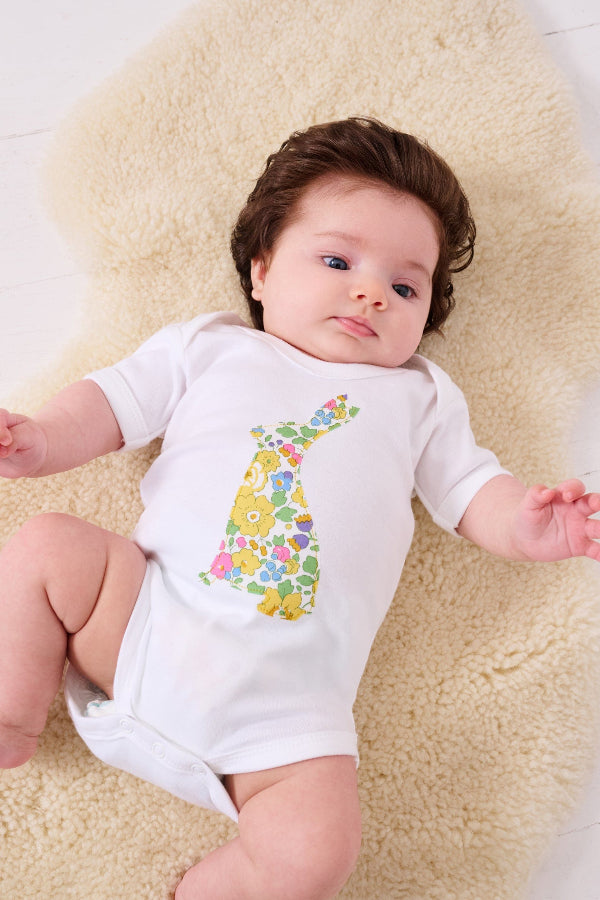A newborn baby girl wearing a white cotton baby bodysuit with an easter bunny made from Betsy Liberty Print sewn onto the front.