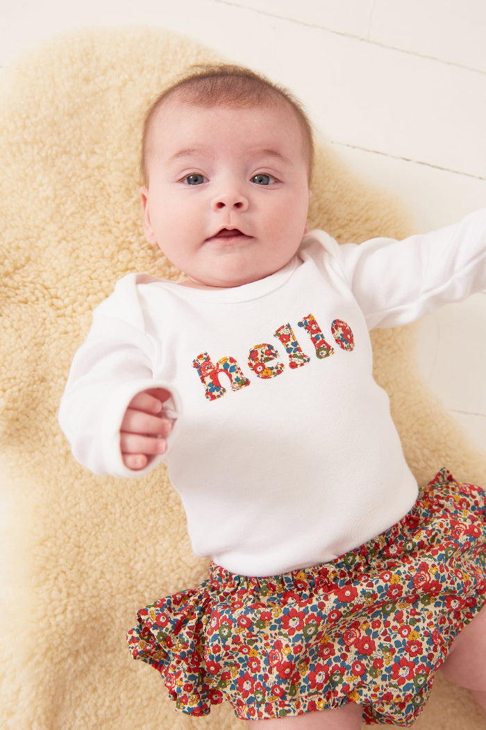 Magnificent Stanley Bodysuit 'hello' Bodysuit in choice of Liberty Print Magnificent Stanley Bodysuit 'hello' Bodysuit. New baby wears a white bodysuit with the word hello on it. the letters are cut from floral liberty print 