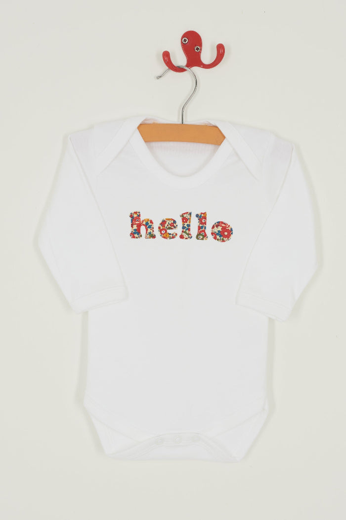 Magnificent Stanley Bodysuit 'hello' Bodysuit in choice of Liberty PrintMagnificent Stanley Bodysuit 'hello' Bodysuit. A white bodysuit with the word hello on it. the letters are cut from  floral liberty print 