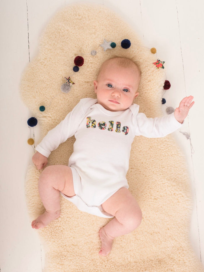 Magnificent Stanley Bodysuit 'hello' Bodysuit in choice of Liberty Print Magnificent Stanley Bodysuit 'hello' Bodysuit. New baby wears a white bodysuit with the word hello on it. the letters are cut from floral liberty print 