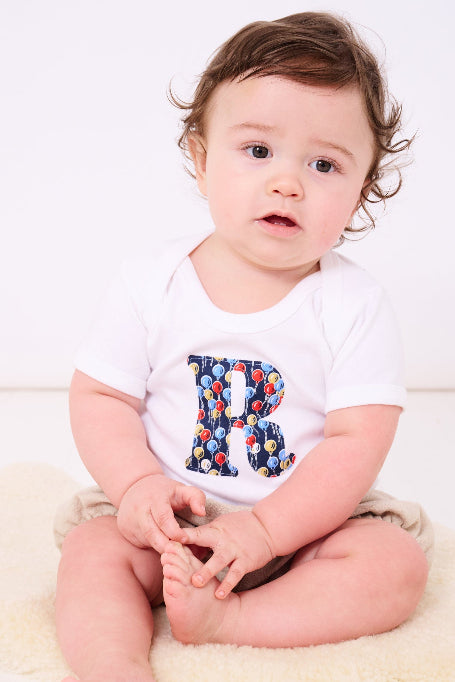 A baby wearing a Personalised Bodysuit in Ethan's Party Liberty Print