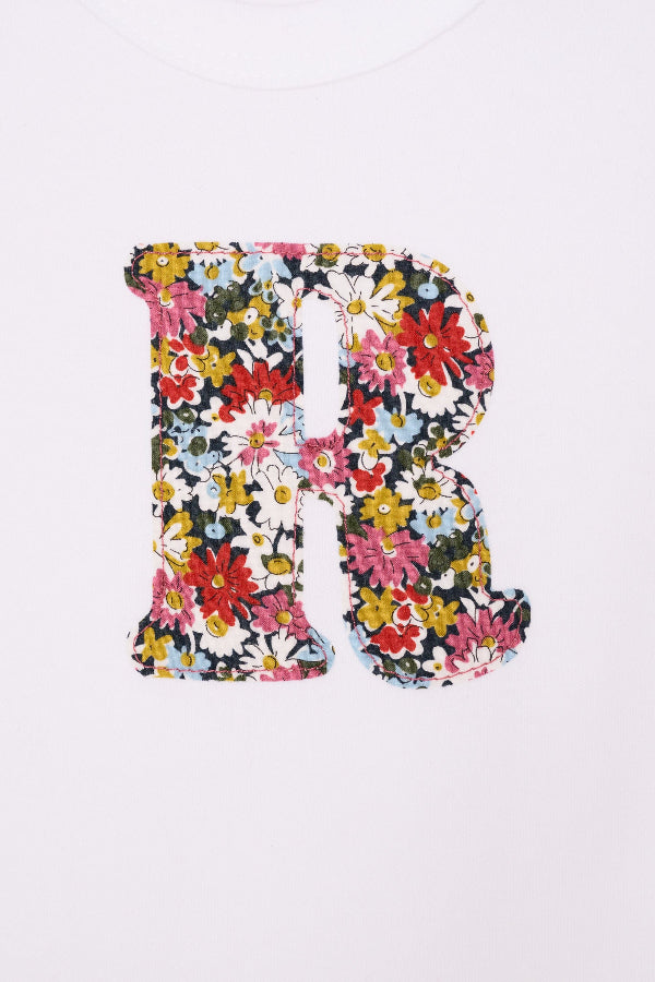 A close up of the letter and stitching on a Personalised initial baby Bodysuit in Libby floral Liberty Print.