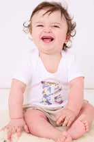 A 6 month old baby boy wearing a Personalised Bodysuit in Tom's Jet Liberty Print with his initial sewn onto the front.