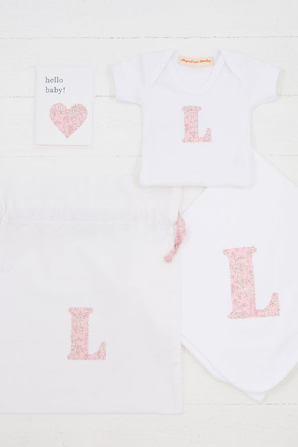 a personalised baby gift set consisting of a hello baby card, a personalised bodysuit, personalised cotton baby blanket and a gift bag, all personalised with Liberty print.