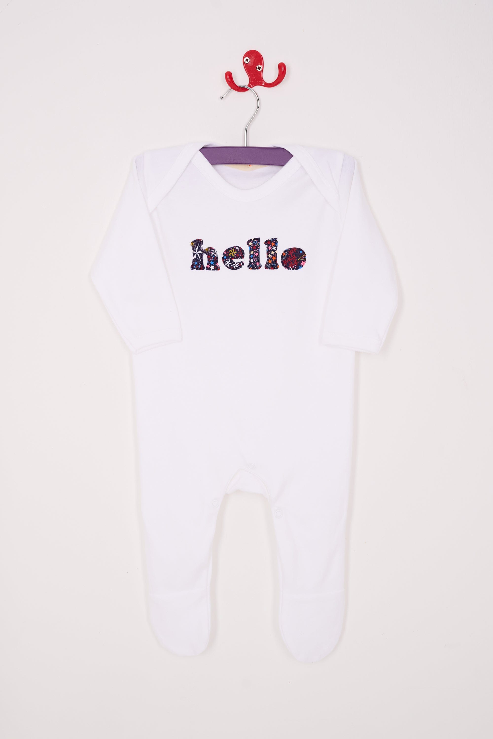 a white cotton romper with the word hello on it. the letters are cut from starry liberty print 