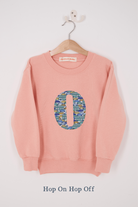 A pink personalised sweatshirt with an initial sewn on to the front. The initial is made from vintage car liberty print