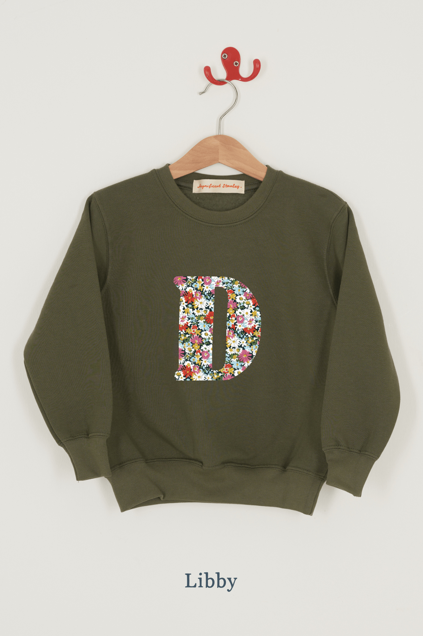 A khaki sweatshirt with an initial on the front. The initial is made from Libby floral Liberty print.