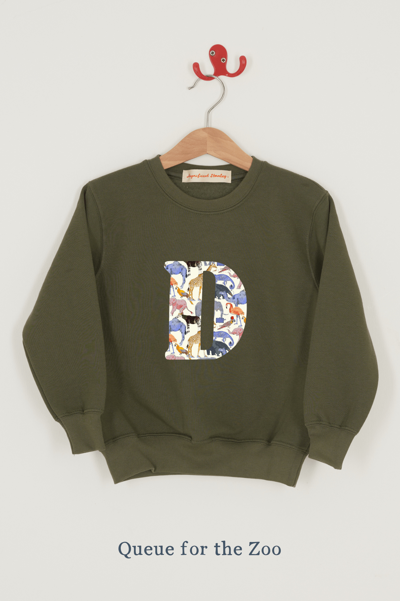 A khaki sweatshirt with an initial on the front. The initial is made from Queue for the Zoo Liberty print.