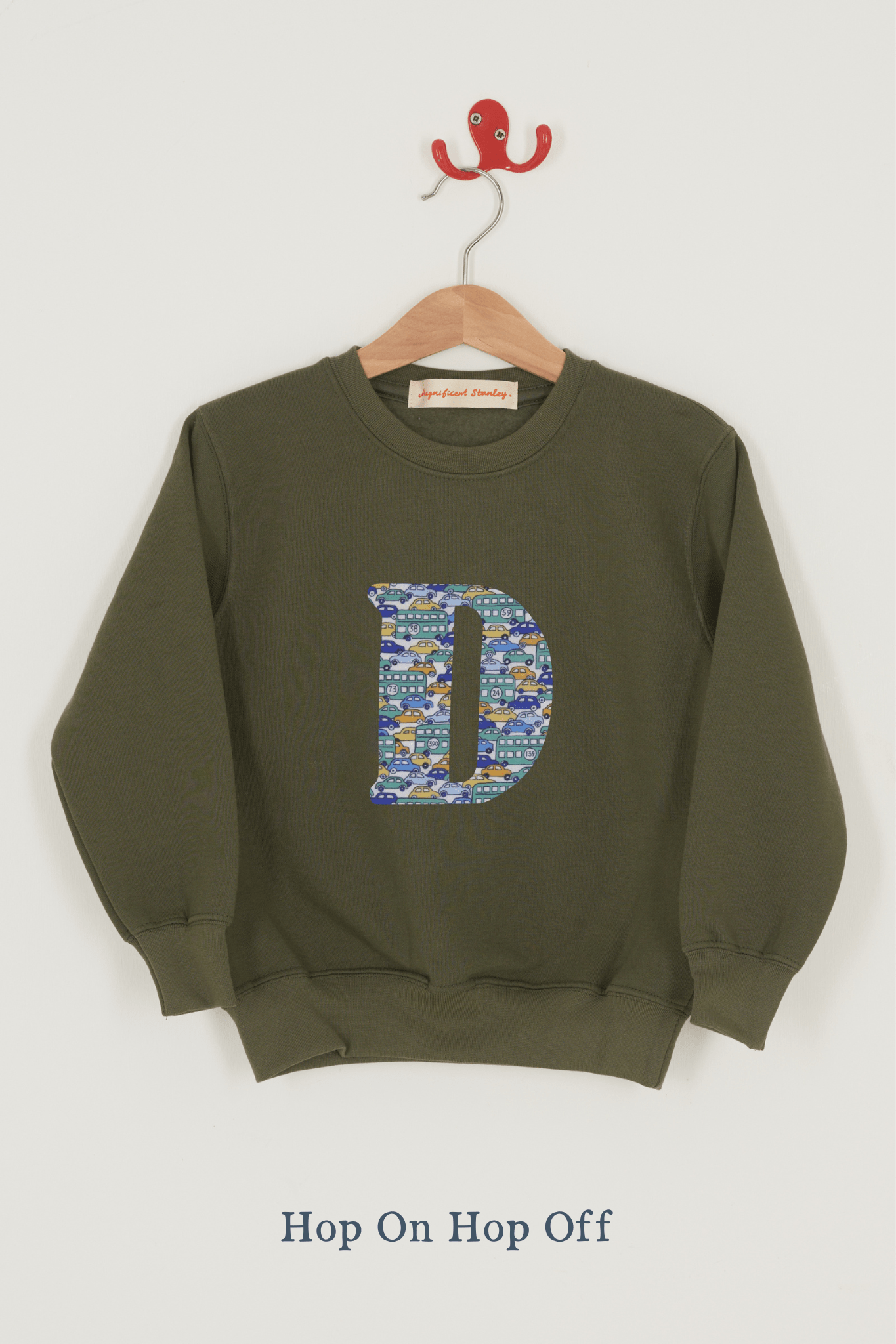 A khaki sweatshirt with an initial on the front. The initial is made from vintage cars Liberty print.