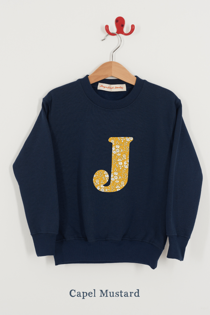A personalised navy sweatshirt with an initial on in capel Liberty fabric.