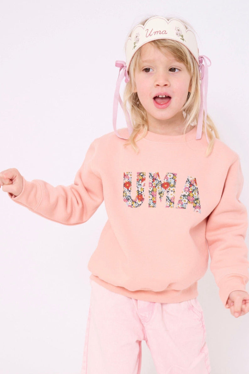 a 4 year old girl wearing a Magnificent Stanley Dusty Pink Sweatshirt  with her name sewn on in Libby floral Liberty Print