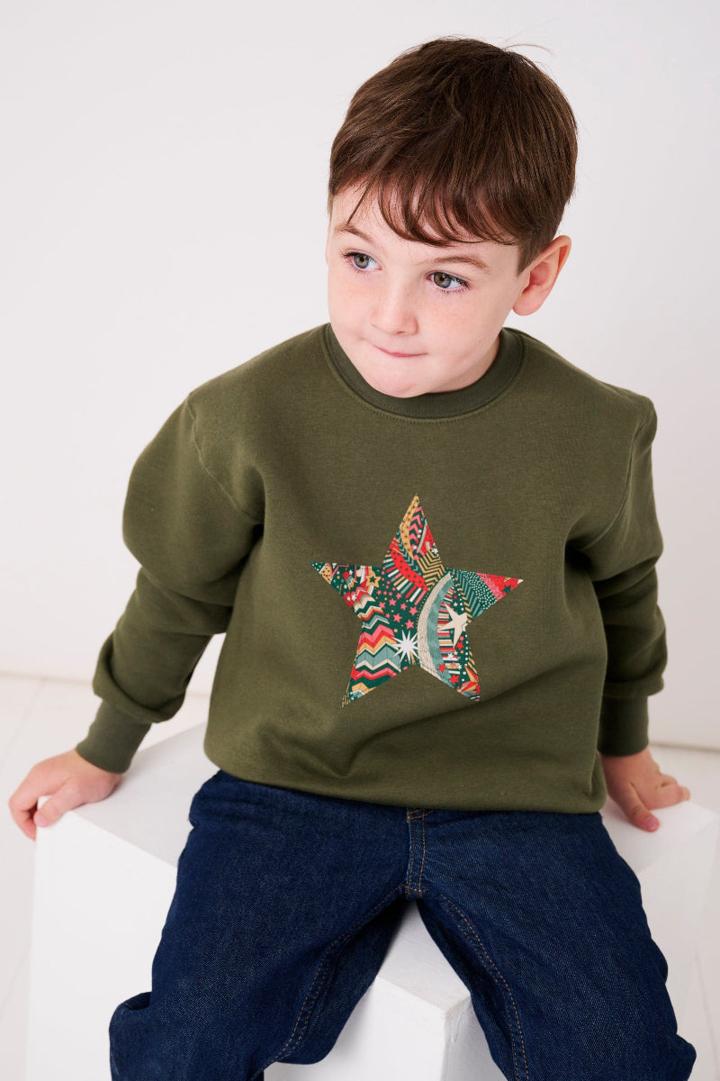 a 5 year old wearing a Magnificent Stanley Khaki Christmas Jumper Sweatshirt with a star on the front made from Liberty Print fabric.