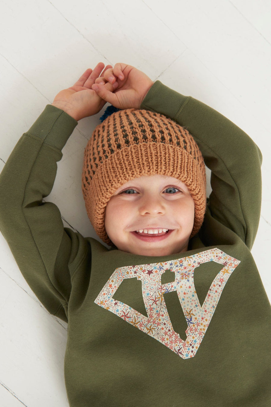 a happy kid in a Magnificent Stanley sweatshirt Superhero  initial Khaki Sweatshirt in star Adelajda Liberty fabric