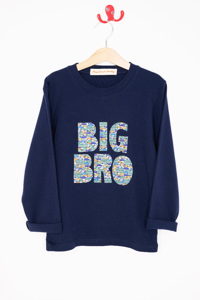 A navy t-shirt with BIG BRO sewn onto it in vintage liberty cars print hanging on a white wall