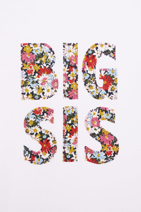 A close up of a white cotton t-shirt with BIG SIS in floral letters on the front. the letters are cut from Liberty print and appliquéd on.