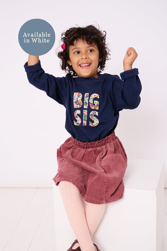 5 year old girl who is a big sister wearing a navy cotton t-shirt with BIG SIS in floral letters on the front. the letters are cut from Liberty print and appliquéd on.