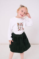 5 year old girl who is a big sister wearing a white cotton t-shirt with BIG SIS in floral letters on the front. the letters are cut from Liberty print and appliquéd on.