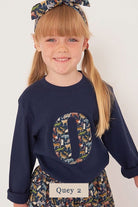a 5 year old girl wearing a personalised kids navy t-shirt with an initial cut from Quey 2 liberty zoo animal print on the front
