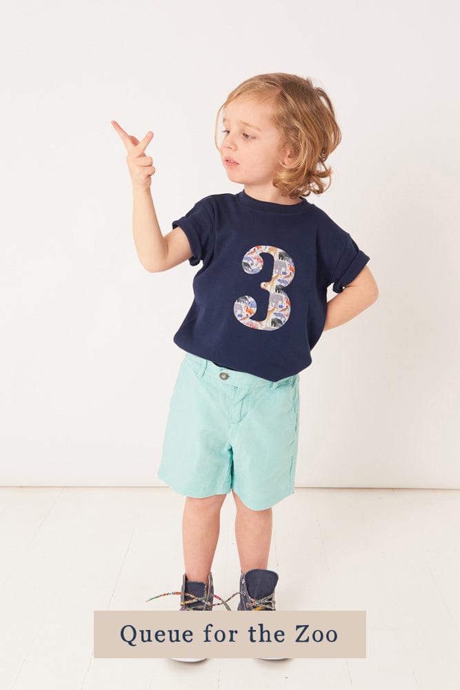 a 3 year old boy wearing a navy birthday t-shirt with a number 3 cut from queue for the zoo liberty animal print on the front