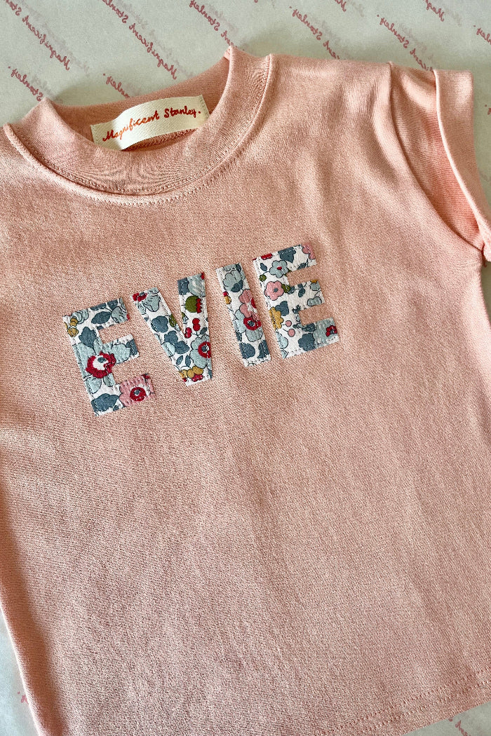 a pink cotton t-shirt with a name written in a floral Betsy Liberty Print.