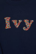 A personalised navy cotton t-shirt with the name Ivy on the front. The name is appliquéd in lowercase letters in Liberty floral fabric.