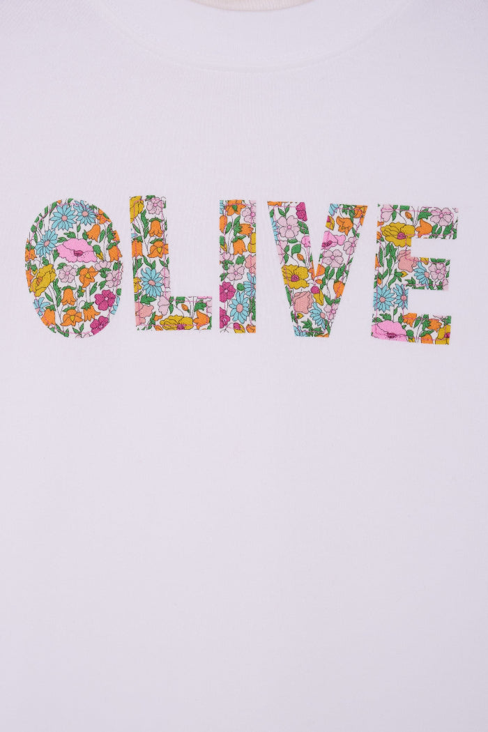 A close up of the stitching on a white personalised t-shirt with her name on the front cut from Poppy Forest liberty print.