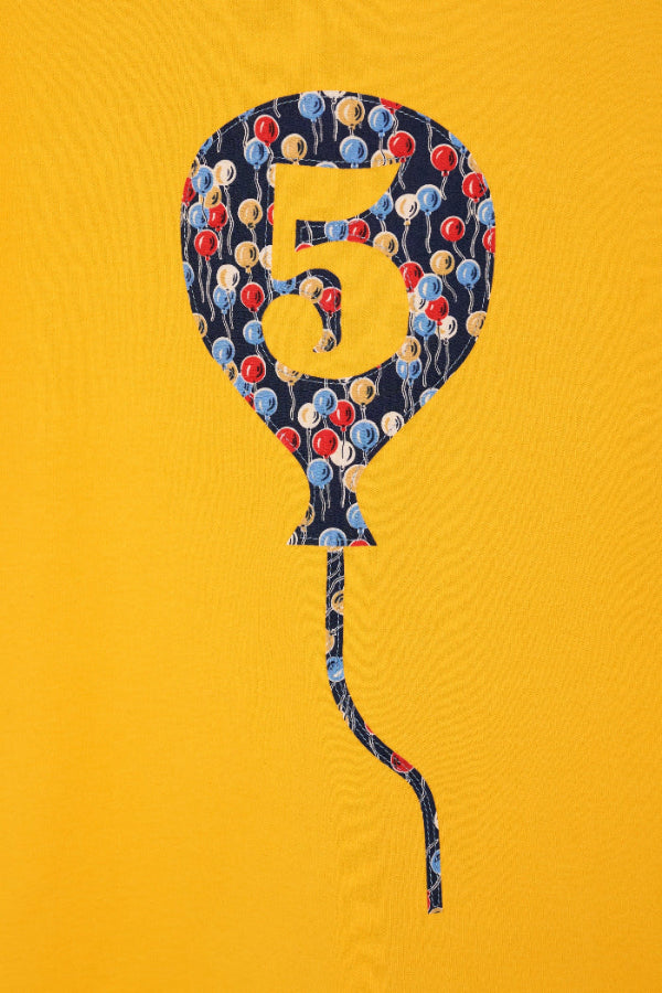 a close up of the appliqué stitching on a Yellow T-Shirt with a Number 5 Balloon on the front made in balloon Liberty Print