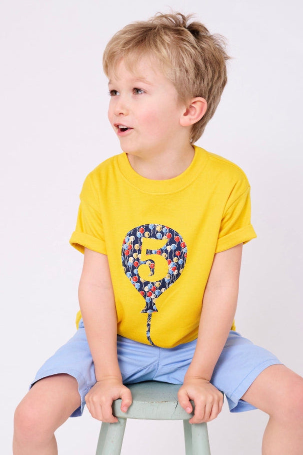 A 5 year old birthday boy wearing a Yellow T-Shirt with a Number 5 Balloon on the front made in balloon Liberty Print