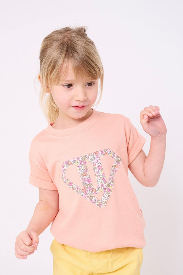A little girl wearing a Superhero Pink T-Shirt in with her initial in Fruit Punch Liberty Print