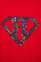 A close up of a red cotton personalised t-shirt with his initial in a superhero emblem Liberty star Adelajda's Wish fabric appliquéd on the front.