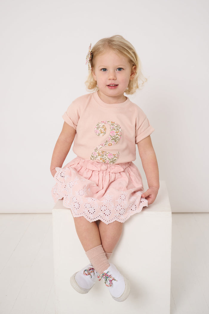 a 2 year old birthday girl wearing a pale pink t-shirt with the number 2 sewn on the front cut from liberty floral Mamie print.
