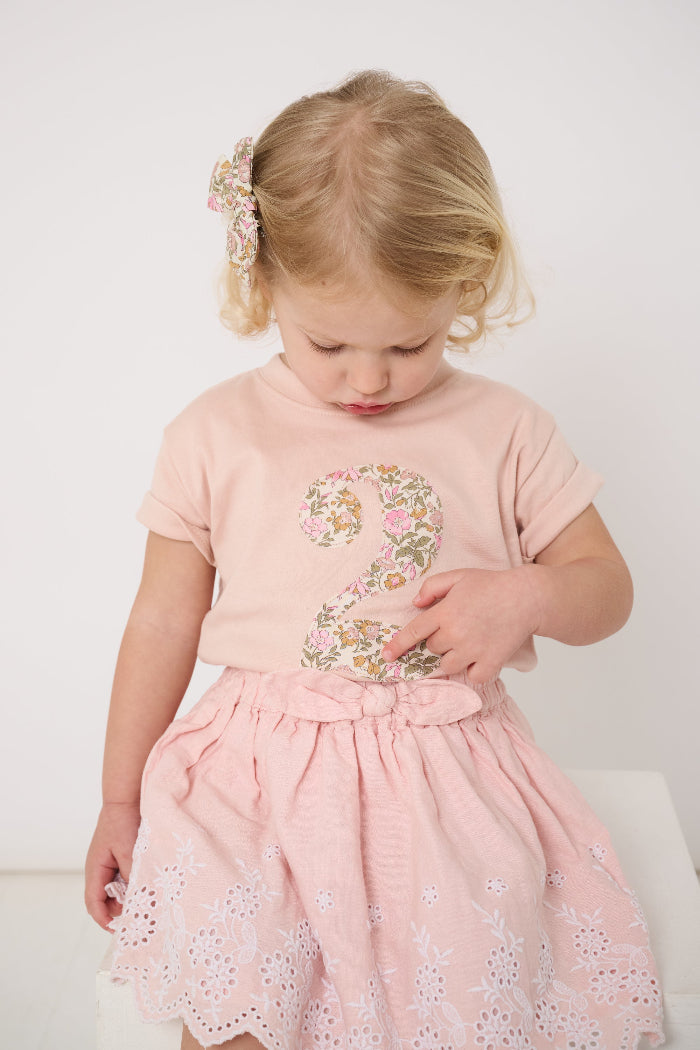a 2 year old birthday girl wearing a pale pink t-shirt with the number 2 sewn on the front cut from liberty floral Mamie print.