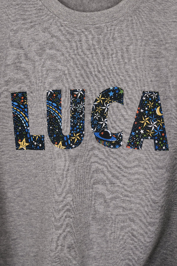 a grey sweatshirt with 'LUCA' in colourful letters in space liberty print.