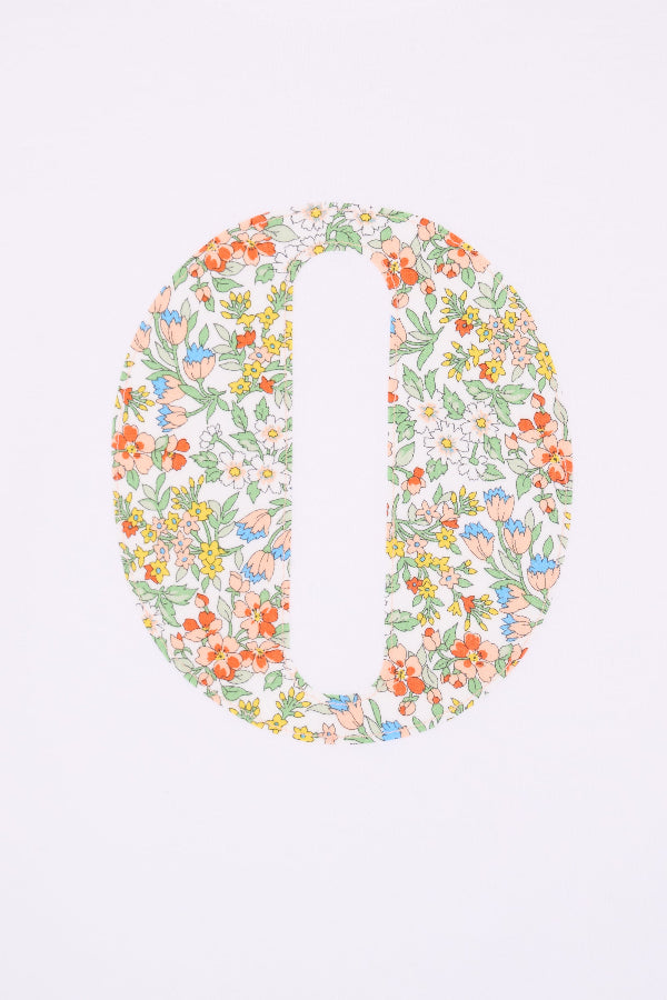 A close up of the stitching on a  summery personalised white cotton t-shirt with an initial cut from Nazanin floral liberty fabric.